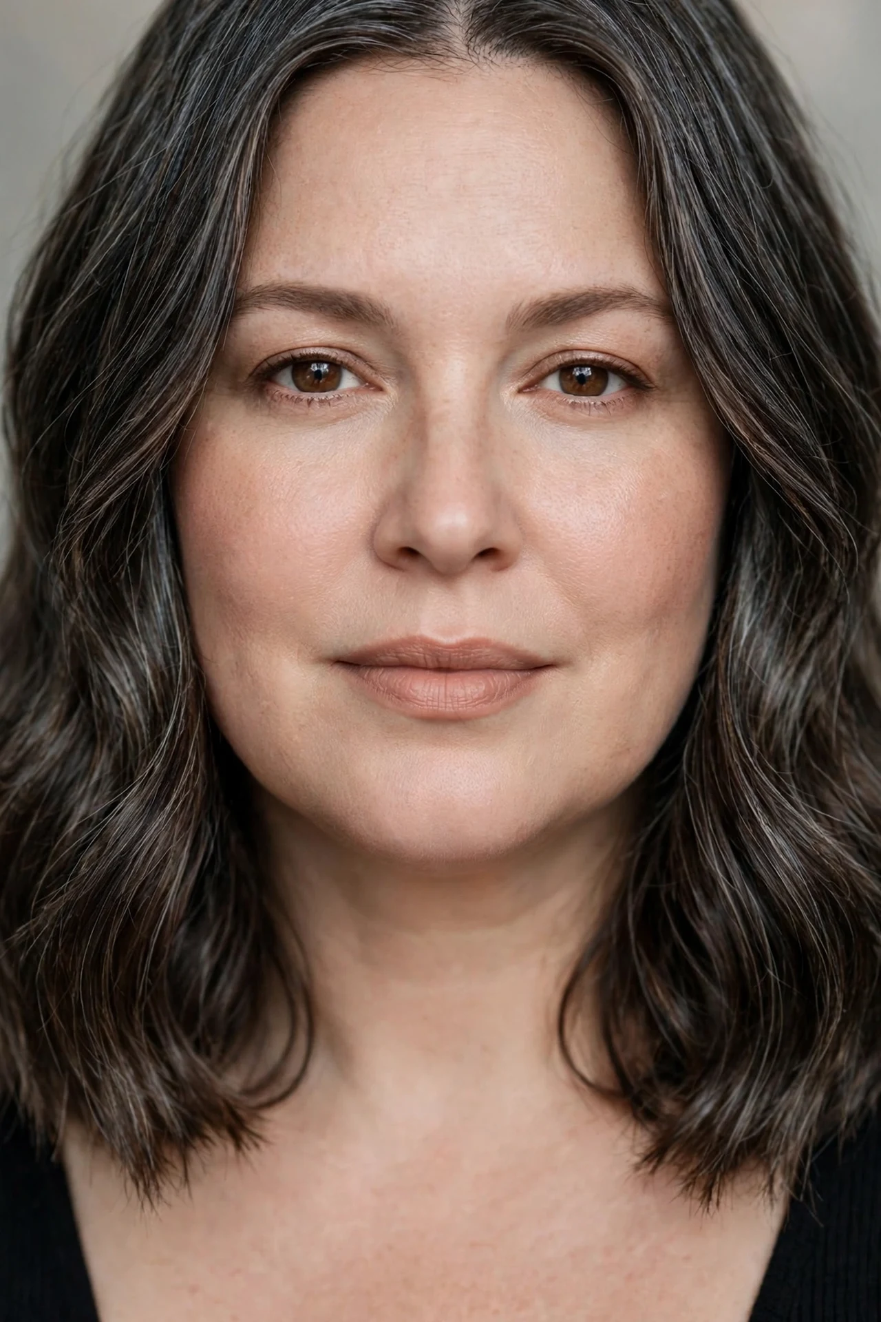 Center part wavy lob falling evenly on both sides of a round faced woman