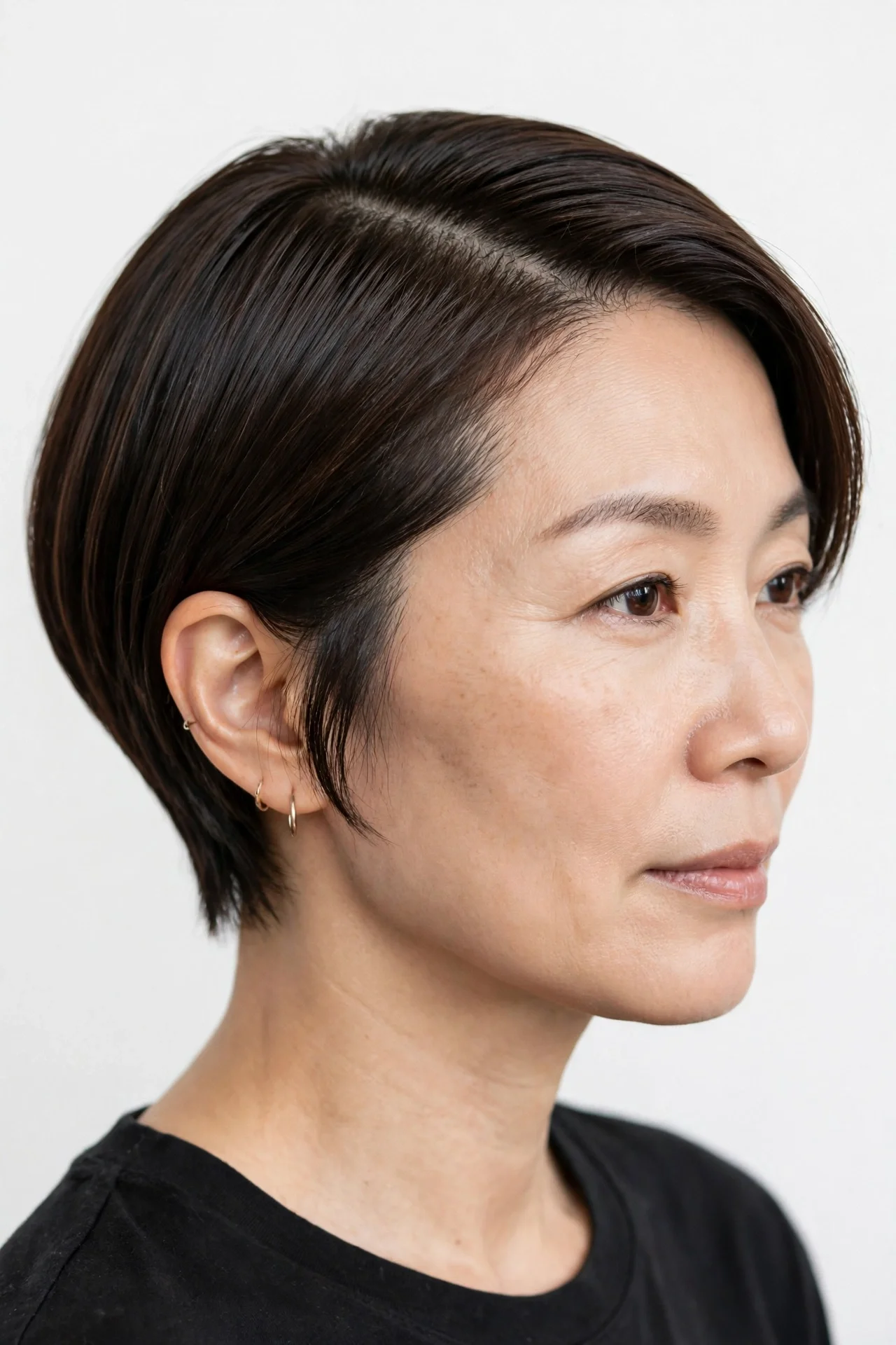 East Asian woman in her 40s with fine dark brown hair in a sleek deep side-part bixie