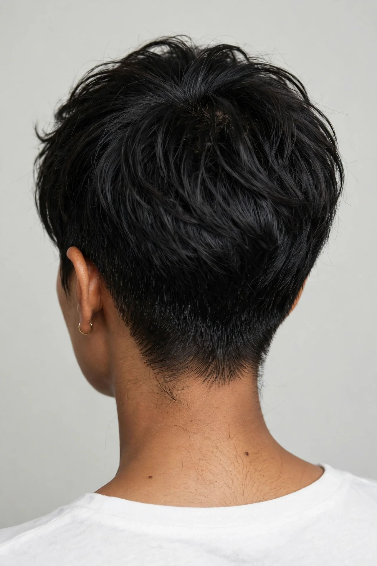 South Asian woman in her 30s with fine black hair in a tapered nape bixie, back view